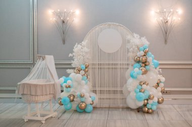 Beyaz yay, yuvarlak kısmı ışıklar, ipler ve harika beşiğin yanında farklı boyutlarda renkli balonlarla dekore edilmiş. Kutlama, düğün, doğum günü, parti, dekorasyon, bayram, etkinlik.