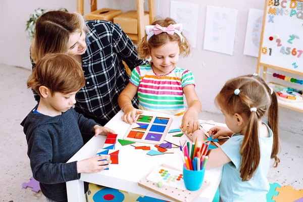 Małe Dzieci Wychowawca Studiuje Składane Kostki Papierowe Figury Geometryczne Biurku — Zdjęcie stockowe