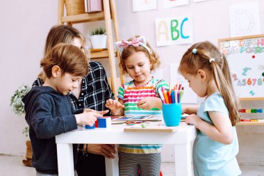 Çocuklu İngilizce öğretmeni çocuk gelişim merkezinde eğleniyor, oyunlar oynuyor, alfabe ve numaralar öğreniyor. Kreş ve bebek bakıcılığı. İngilizce, İngilizce ve Amerikan okulları.
