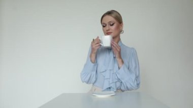 Resmi giyinmiş utangaç, güzel sarışın bir kadının videosu. Masaya oturup çay ya da kahve içerek hediye olarak büyük pembe bir çiçek alıyor. Kafede sürpriz. Minnettar ve onurlu hissediyorum. Yüksek kalite, 4 bin. 