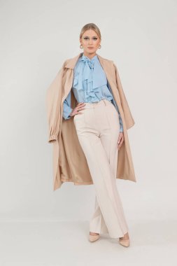 Hassas bluzlu, pelerinli ve pantolonlu, beyaz arka planlı, bedava fotokopi alanı olan güzel, ince bir kadının tam boy fotoğrafı. İş adamları, temel kadın kıyafetleri, günlük ofis kıyafetleri, mevsimlik görünüş..