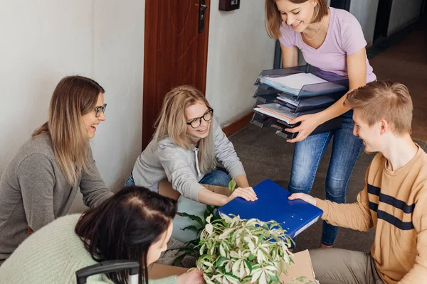 Laughing, cheerful women and man colleagues moving, preparing to business travel. Packing stuff, baggage on holiday vacation. Sort paper documents, folders and contracts. Business trip and work travel