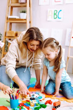 Dikey adanmış, ödüllü bayan öğretmen mantık oyunları oynar ve anaokulları için çocuk gelişim merkezinde küçük bir kızdan öğrenir. Erken eğitim. Beyin ve motor aktivitenin çocuk bakımı