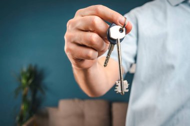 man holds a house key in his hand. the key to the new house. new housing concept