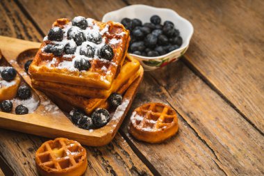 belgian waffles with berries on a dark background. sweet waffles with blueberries for breakfast