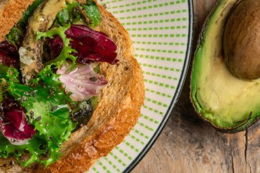 toast with avocado. vegetarian breakfast. Vegan or Vegetarian Toast with mashed avocado, arugula served on wooden board