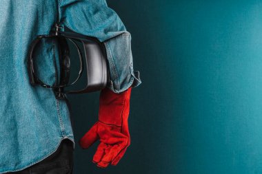 an iron worker wearing red protective gloves and a welder's protective mask. factory worker. labor day