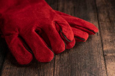 red welder gloves on a wooden background. worker's equipment