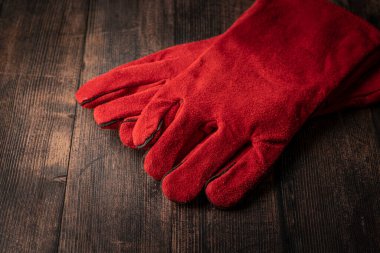 red welder gloves on a wooden background. worker's equipment
