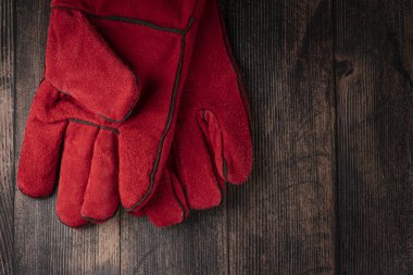 red welder gloves on a wooden background. worker's equipment
