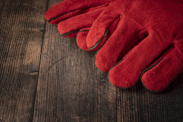 red welder gloves on a wooden background. worker's equipment