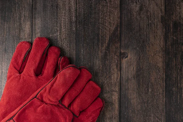 red welder gloves on a wooden background. worker's equipment