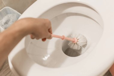 Adamın eli tuvalet fırçasını tutuyor ve tuvaleti temizliyor. Tuvaletteki temizlik ve hijyen kavramı..