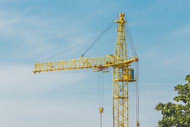 Mavi gökyüzüne karşı kule yapımı sarı vinç.