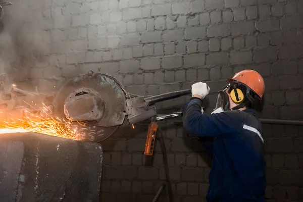 保護ヘルメット マスク 全体の男性労働者は 工業プラントのワークショップで火花を飛んで鋳鉄コンクリートチューブのための重い研削装置を管理します — ストック写真