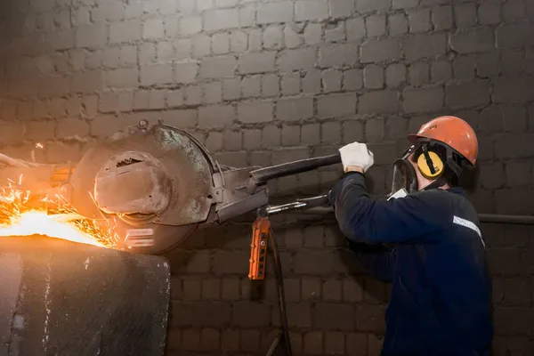 保護ヘルメット マスク 全体の男性労働者は 工業プラントのワークショップで火花を飛んで鋳鉄コンクリートチューブのための重い研削装置を管理します — ストック写真