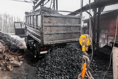 Çöp kamyonu, sanayi bölgesindeki vinç kaldırma mekanizmasının yanındaki kolajlı kömürden dökülen çöplüğe boşaltılmış..