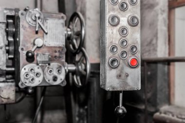 Fabrikada endüstriyel ekipman düğmeleri olan eski, kirli asma sistemi ve kontrol paneli.