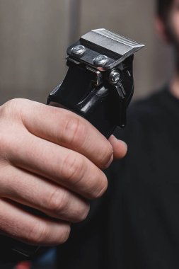 Adamın biri elektrikli tıraş makinesi tutuyor. Kuaförlük.