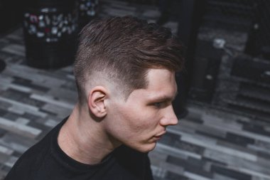 Kafkas görünümlü, koyu saçlı, modern saç kesimli, kuaförde ya da berber dükkanında genç ve ciddi bir adam portresi..