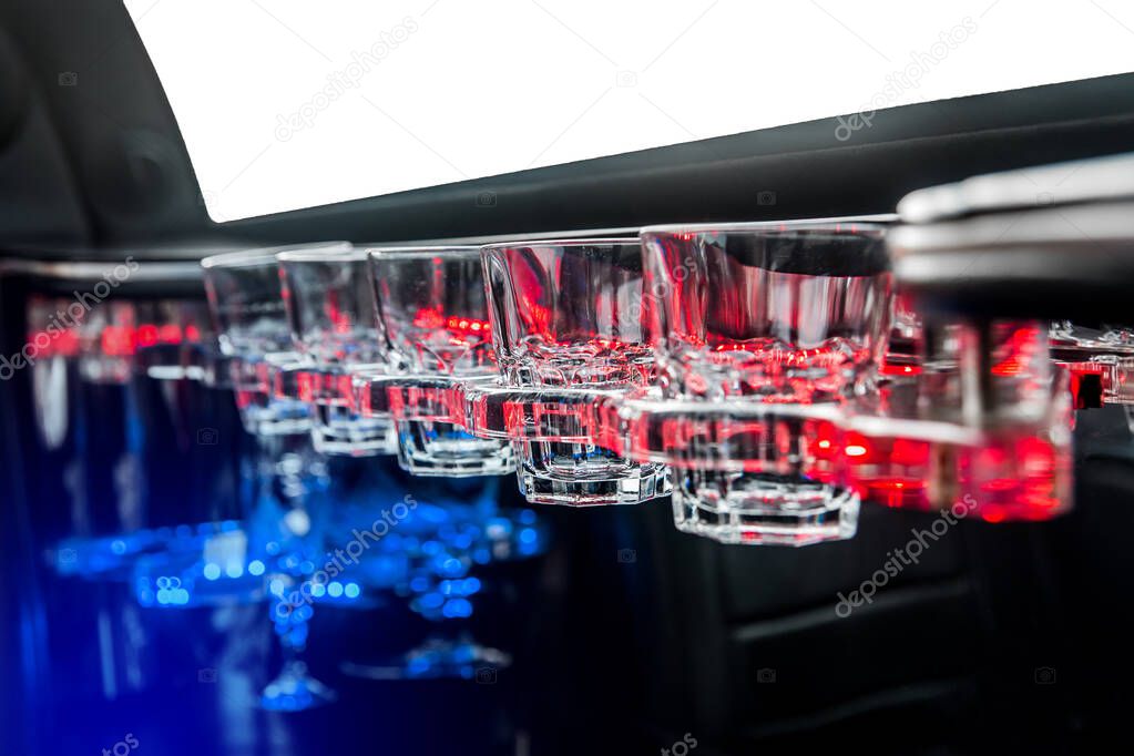 Glass glasses in neon lighting inside the luxury car limousine.