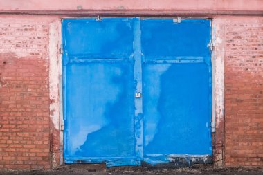 Eski kirli yıpranmış demir depo mavi kapı tuğla bina duvarlı terk edilmiş mimari.