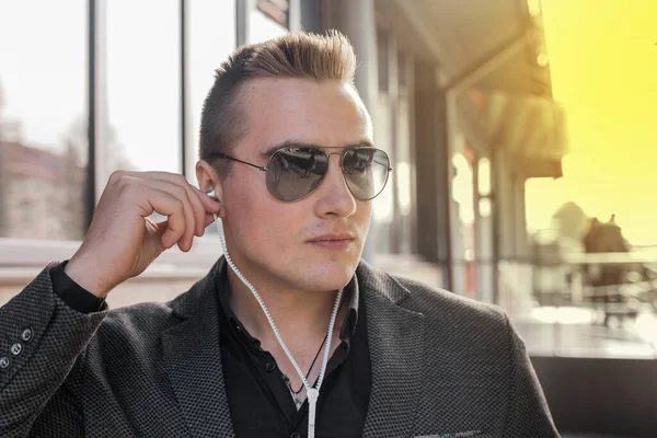 출신의 청년의 선글라스를 매력적 사업가 길거리에서 헤드폰으로 음악을 — 스톡 사진
