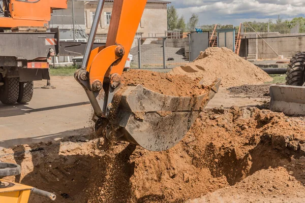 Kazı işe yarıyor. İnşaat alanında yerde ağır bir kürekle traktör kovası kazıyor..