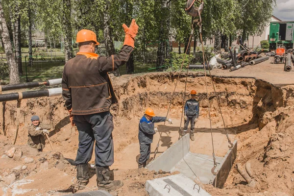 Belarus, Minsk Bölgesi - 20 Mayıs 2020: Tulumlu bir ustabaşı ve koruyucu bir kask, sanayi bölgesinin inşaat alanındaki beton yapıları kaldırma sürecini kontrol ediyor..