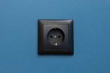 Tek siyah soket enerji kaynağı ev enerjisi mavi duvar arka planında elektrik, kapat.