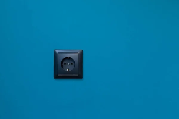 蓝墙背景图上的单座黑插座电源家用电源 — 图库照片