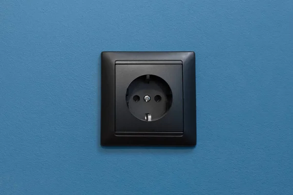 Tek siyah soket enerji kaynağı ev enerjisi mavi duvar arka planında elektrik, kapat.