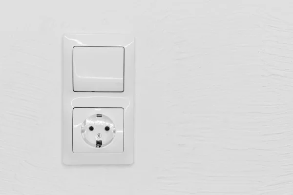Socket and light off turn on button on the background of the switch white wall of the house, close up.