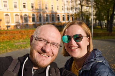 Birbirini seven mutlu bir çift, şehirde selfie çekiyor. Güzel insanların yaşam tarzı. Gözlüklü kel adam ve güneş gözlüklü çekici kadın. Kafkas çifti.