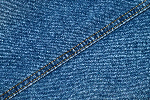斜めの縫い代でブルーのジーンズの質感のクローズアップ。デニムのテキスタイルの背景。服生地. — ストック写真