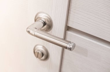 Beyaz ahşap iç kapıya metalik krom saplı. Modern kapı kolu. Seçici odak.