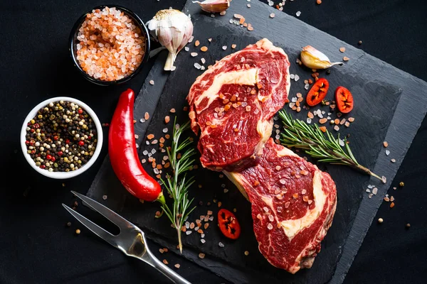 Baharatlı Çiğ Biftek Siyah Arka Planda Otlar Tuz Biber Sarımsak — Stok fotoğraf