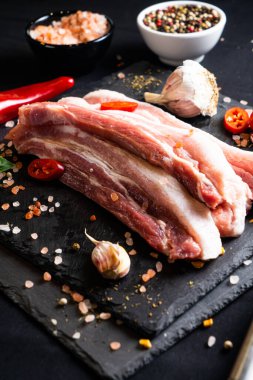 Koyu arkaplanda pişmeye hazır baharatlı çiğ domuz eti.