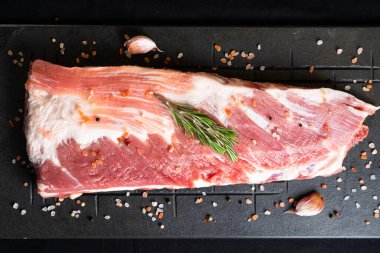 Tahtada domuz eti, pirzola, koyu arkaplanda baharatlar.