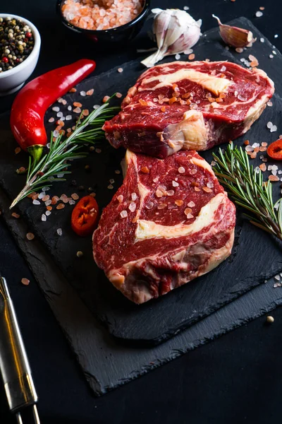 Rauwe Biefstuk Met Specerijen Kruiden Zwarte Achtergrond Zout Peper Knoflook — Stockfoto
