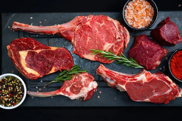 Rohe Rindersteaks Mit Salz Gewürzen Und Kräutern Auf Schwarzem Hintergrund — Stockfoto