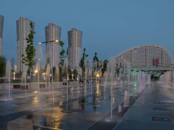 Akşamları Khodynskoe sahasındaki parkta gökdelenler ve çeşmeler.