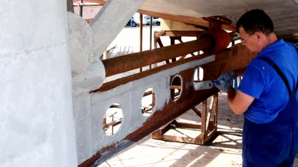 Працівник малює метал старого іржавого корабельного гвинта на верфі в порту . — стокове відео