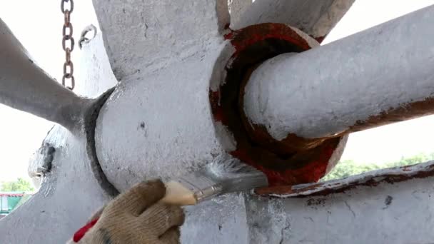 Worker paints metal of old rusty ship propeller at shipyard in port. — Stock Video