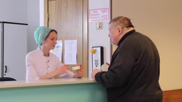 Sjuksköterska pratar med fet man på kliniken. — Stockvideo