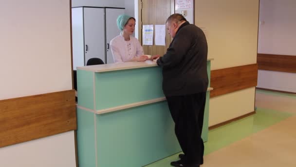 Sjuksköterska tar medicinskt kort från fett mannen i klinik. — Stockvideo