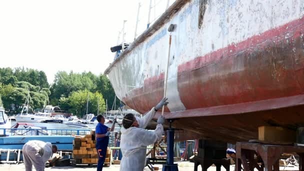 Працівник малює пензля металеві передній частині корабля на верфі в порту Москви. — стокове відео