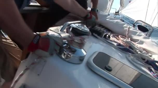 L'homme tire la corde sur le treuil sur le yacht à voile en mouvement. — Video