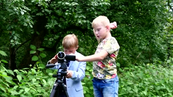 小男孩与录影照相机射击影片关于自然绿色公园背景. — 图库视频影像