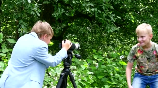 Młodzi chłopcy z kamerą wideo strzela film o charakter tło zielony park. — Wideo stockowe